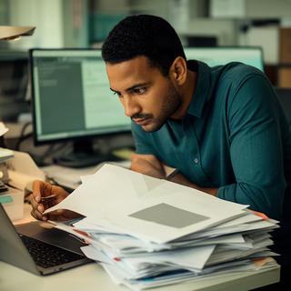 Ceazer Halouy, periodista de actualidad, consultando documentos en su mesa de trabajo
